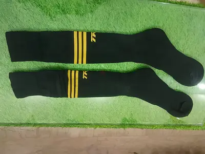 Pair of long black athletic socks with yellow stripes