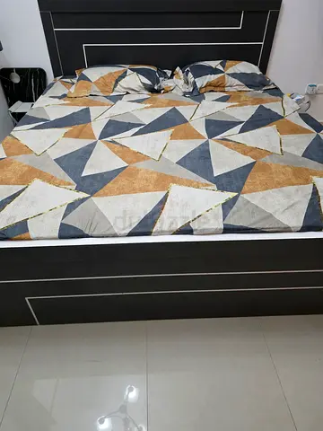 King bed with geometric duvet cover and dark wood frame