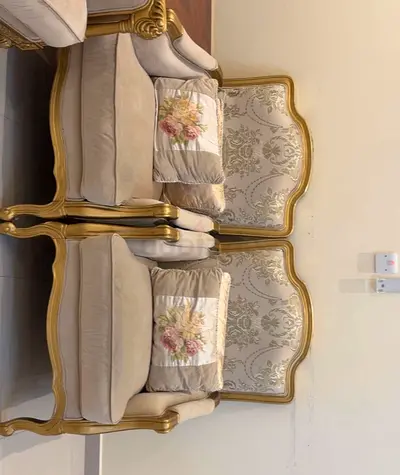 Pair of classic beige upholstered accent chairs with carved wooden frames