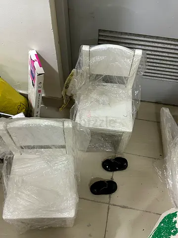 Pair of white dining/accent chairs wrapped in protective plastic