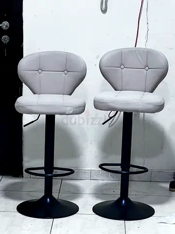 Pair of adjustable swivel bar stools with beige cushioned seats