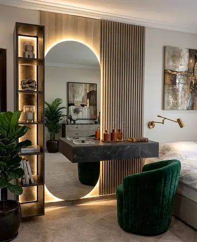 Modern bedroom vanity setup with illuminated mirror and green velvet chair