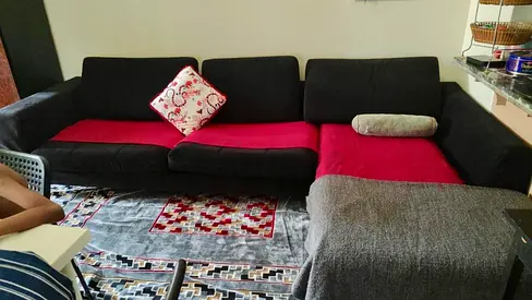 L-shaped black fabric sofa with red seat covers - good condition