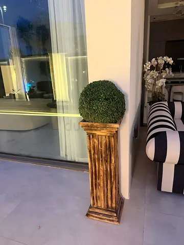 Decorative faux boxwood topiary on tall rustic wooden pedestal