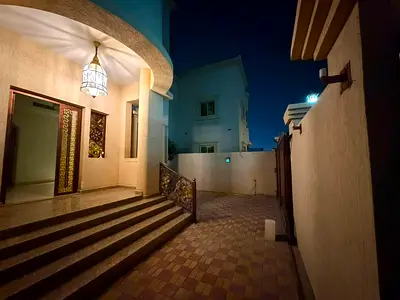 Corner villa in Al Rawda 3 Ajman, 5 master bedrooms, maid room, majlis, living room, 2 kitchens, roof, central AC, spacious for families.