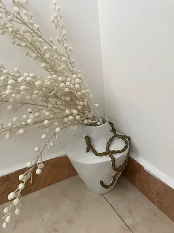 White ceramic vase with decorative gold rope and artificial stems