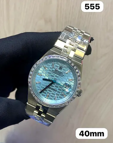 watch appears to be a Rolex Land-Dweller (Ref. 127386TBR-0001), featuring a platinum case, an ice-bl