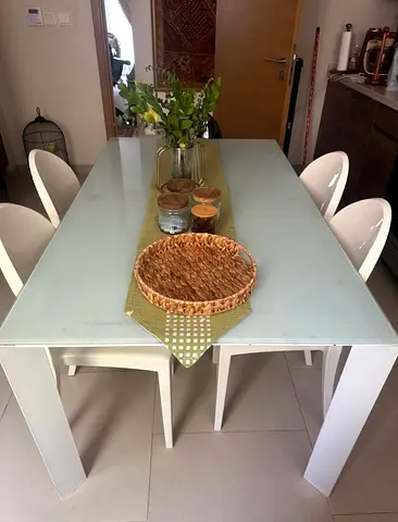White glass-top dining table with 4 modern chairs