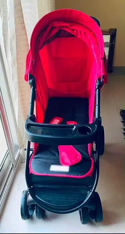 Red baby stroller in good used condition, includes cup tray and sun canopy