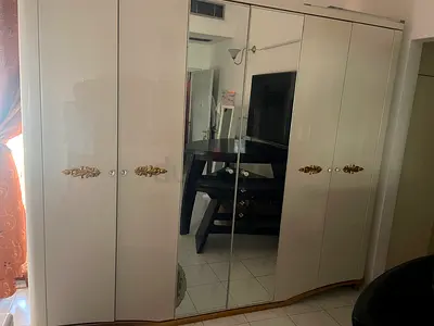 White glossy 6-door wardrobe with mirrored center panels and gold handles