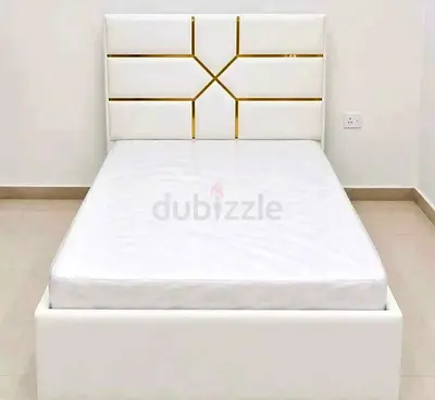 Single white upholstered bed with padded headboard and mattress