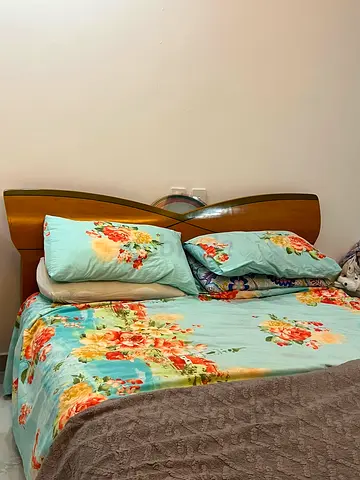 Double bed with wooden headboard and floral bedding