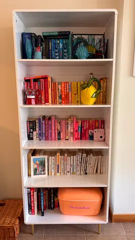 Free standing white bookshelf with five shelves and small gold feet.