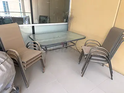 Outdoor glass-top dining table with 6 stackable patio chairs