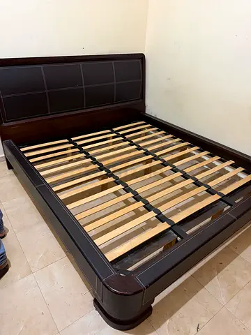 Dark wooden queen bed frame with slats and padded headboard