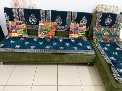 L-shaped fabric sofa with patterned covers and throw cushions - good condition