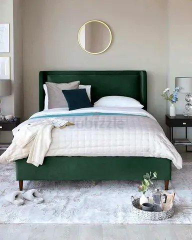Green upholstered double bed with velvet headboard and wooden legs