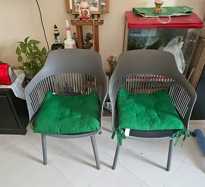 Pair of modern grey plastic dining chairs with green seat cushions