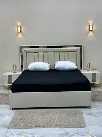 Modern upholstered queen bed with mirrored headboard and matching bedside tables