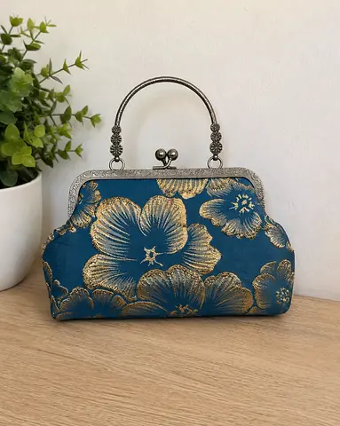 Vintage-style blue and gold floral clutch handbag with metal frame handle