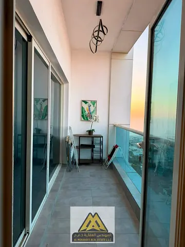 Luxury fully furnished apartment for sale with automatic blinds and Alexa control, featuring a balcony with an open view, located in Ajman One Towers