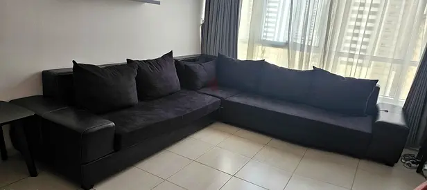 Large L-shaped black fabric and leather sofa — acceptable condition