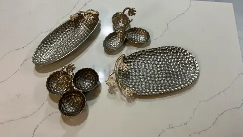 Set of decorative metal bowls and trays with pineapple accents.