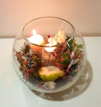 Decorative glass bowl with candles and dried floral arrangement