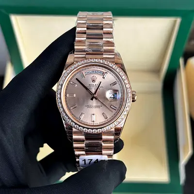 This is a Rolex Day-Date 40 in Everose gold with a diamond-set bezel and baguette-cut diamond