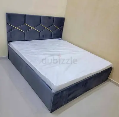 Grey upholstered double bed with padded headboard and storage base
