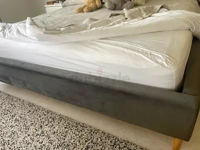 Grey upholstered king-size bed frame with wooden legs