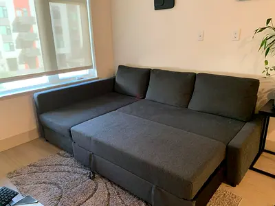 Dark grey L-shaped sofa bed, good condition