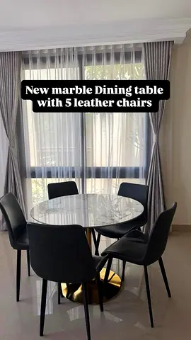 Round white marble dining table with 5 black leather chairs
