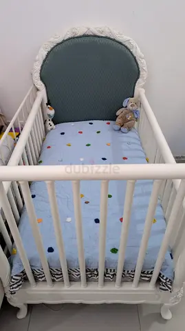 White wooden baby crib with mattress and bedding