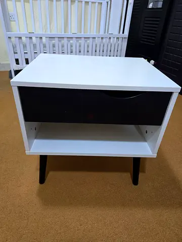 Compact white bedside table with drawer and black legs