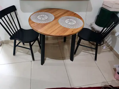 Small round wooden dining table with 2 black chairs