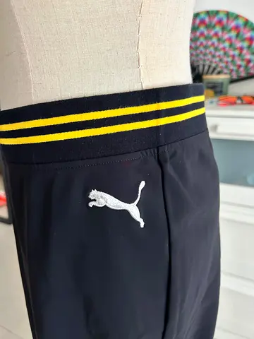 Black athletic skirt PUMA with yellow-striped waistband and cat logo - size M