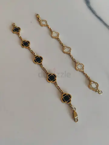 Pair of unisex gold-tone clover link bracelets — one black enamel, one clear stone