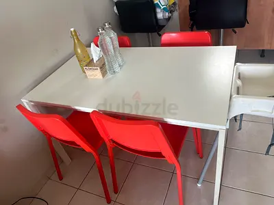 Simple white dining table with 4 orange chairs - good condition. Perfect in and out hardly used.