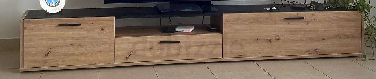 Low-profile wooden TV cabinet with three drawers — light oak finish