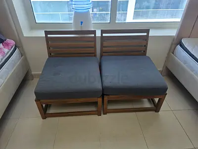 Pair of wooden armless lounge chairs with grey cushions