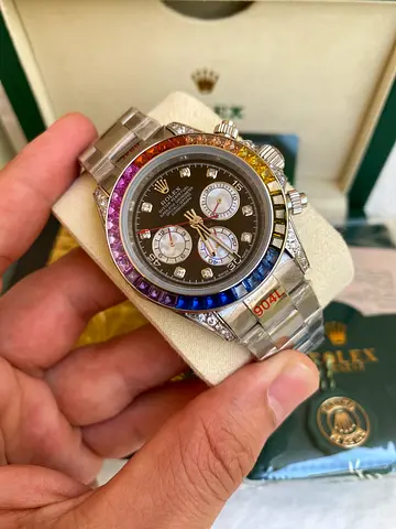 This watch is a Rolex Daytona Rainbow RBOW, featuring a black dial and a bezel set with colored gems