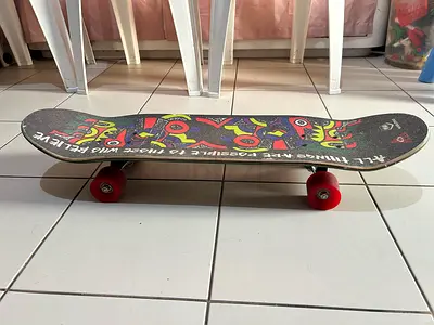 Used standard skateboard with colorful deck and red wheels
