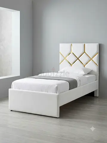 Single white upholstered bed with gold-accented headboard
