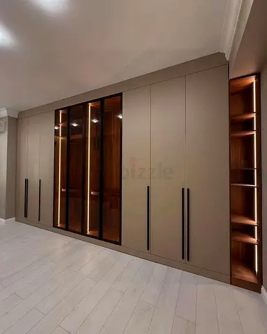Custom built-in bedroom wardrobe with glass doors and LED-lit shelves