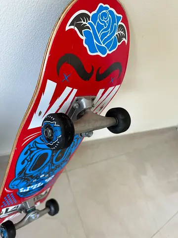 Used red skateboard with blue skull graphic - good condition