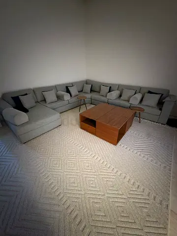 Large light grey sectional sofa with coffee table and tables