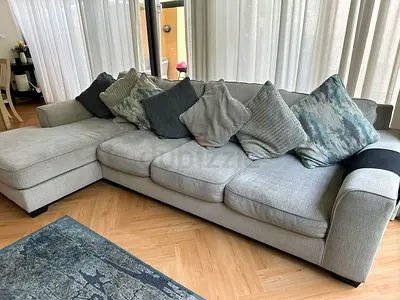 Large L-shaped grey fabric sofa with chaise and cushions