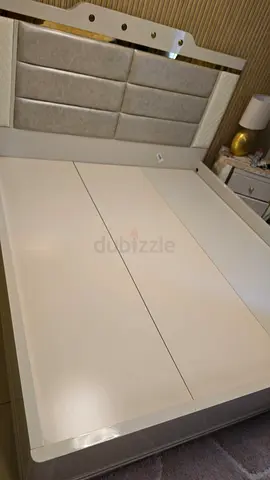 White queen bed frame with padded headboard and storage base — good condition
