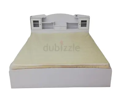White double bed with built-in headboard storage and side shelves